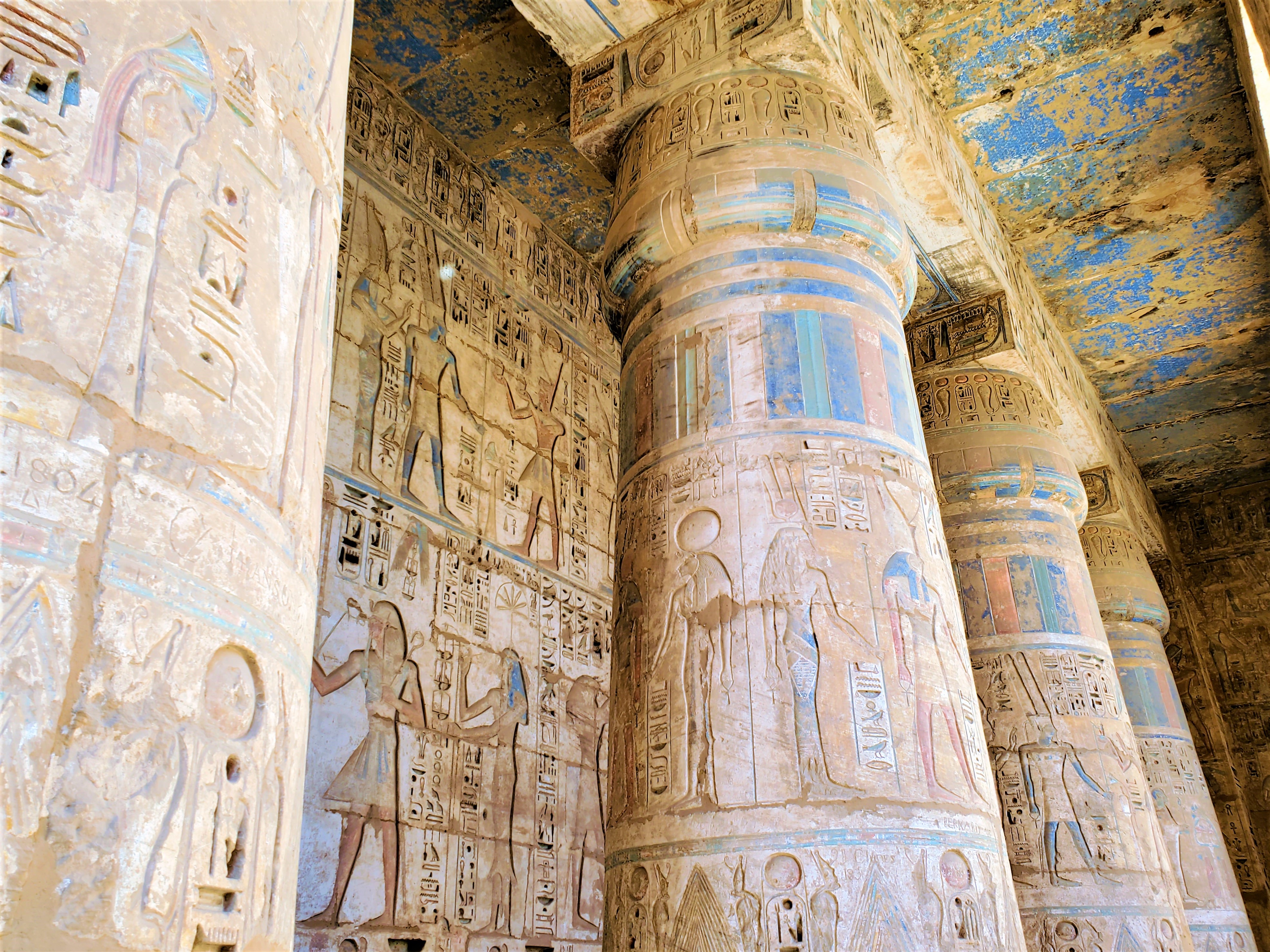Beautiful colors and skilled carvings cover the ceiling and and majestic columns at Medinet Habu in Luxor, Egypt